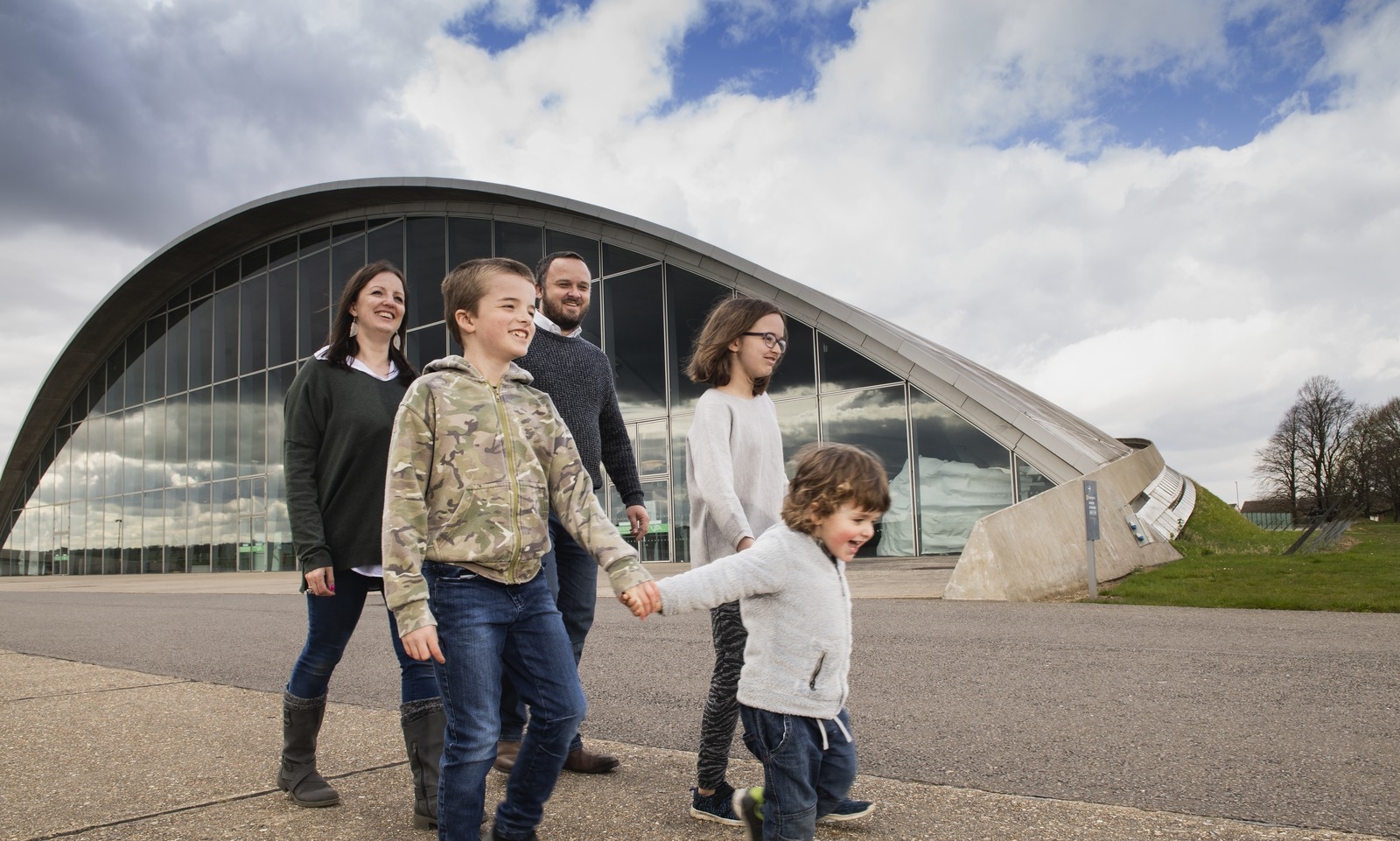 Young family walking in front of the American Air Museum at IWM Duxford
